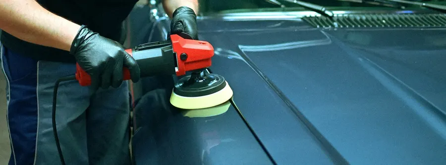 Lackpolitur mit einer Poliermaschine auf einer dunkelblauen Motorhaube