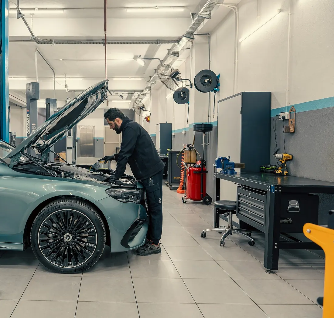 Helle, aufgeräumte Werkstatt mit Hebebühne und einem Fahrzeug bei der Inspektion