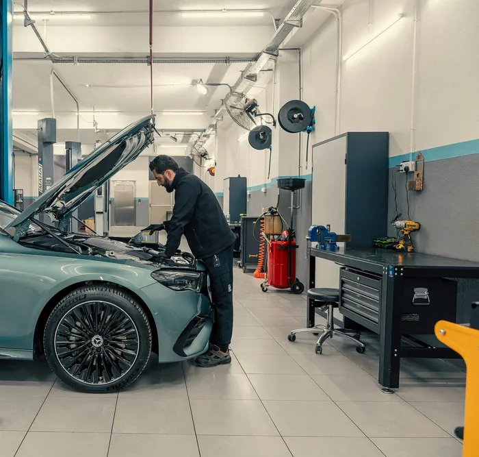 Mechaniker füllt Motoröl bei einer Inspektion in einer hellen Werkstatt nach